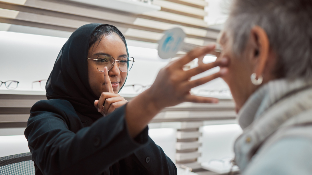 Optometry, vision and eye test with an islamic woman optician working to diagnose a customer. Docto.
